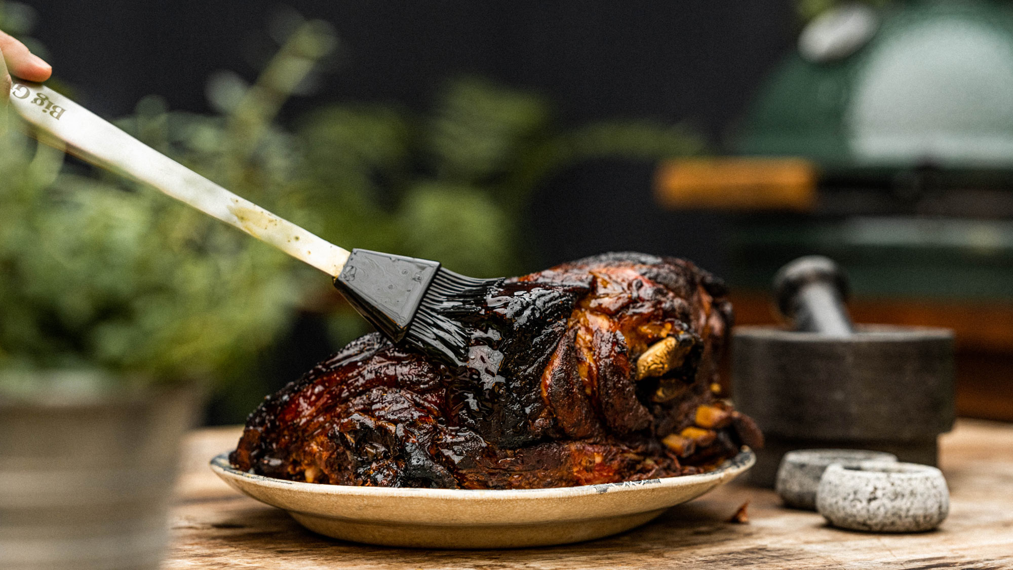 Stainless steel silicone brush basting a pork shoulder