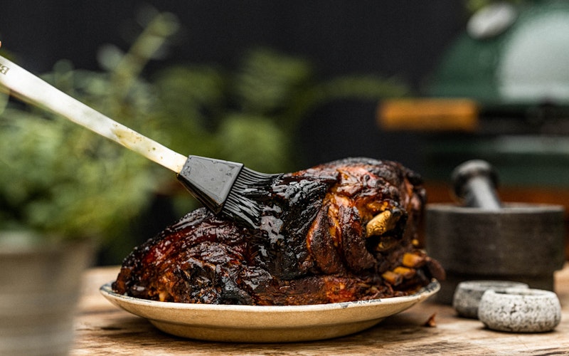 Stainless steel silicone brush basting a pork shoulder