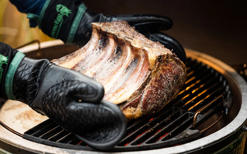 Heat Resistant Silicone BBQ Mitt with Fabric Cuff holding a rib of beef